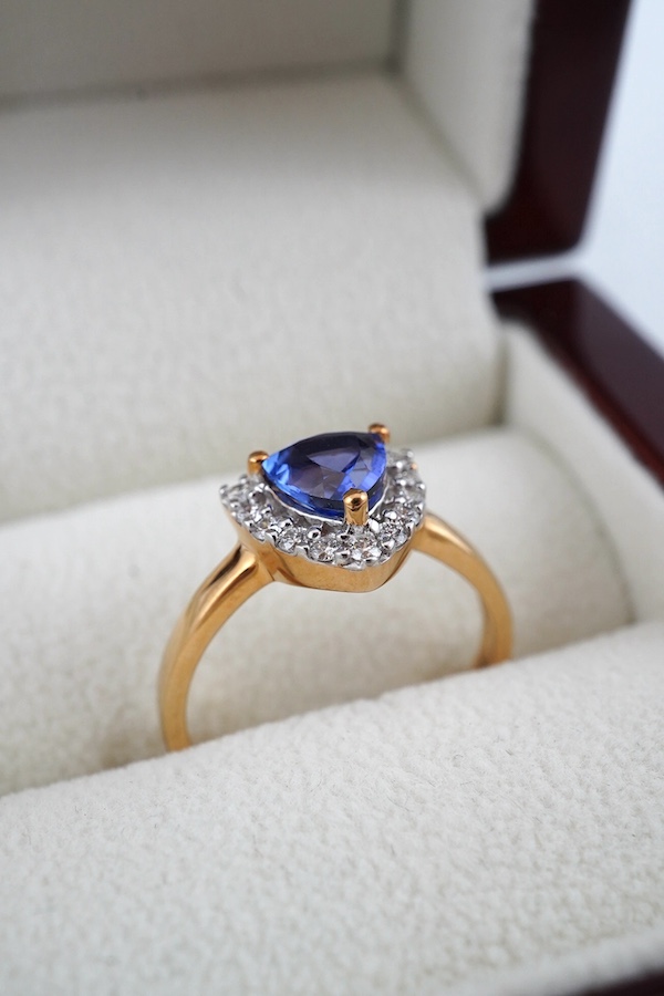 A modern 18ct gold, tanzanite and diamond cluster set ring, with AnchorCert report estimating the tanzanite to weight 1.01ct, size O, gross weight 4.4 grams. Condition - good